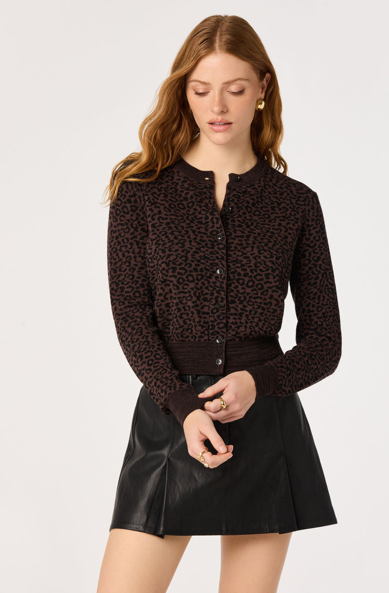 Woman wearing a black and brown leopard print cardigan and a black leather skirt.