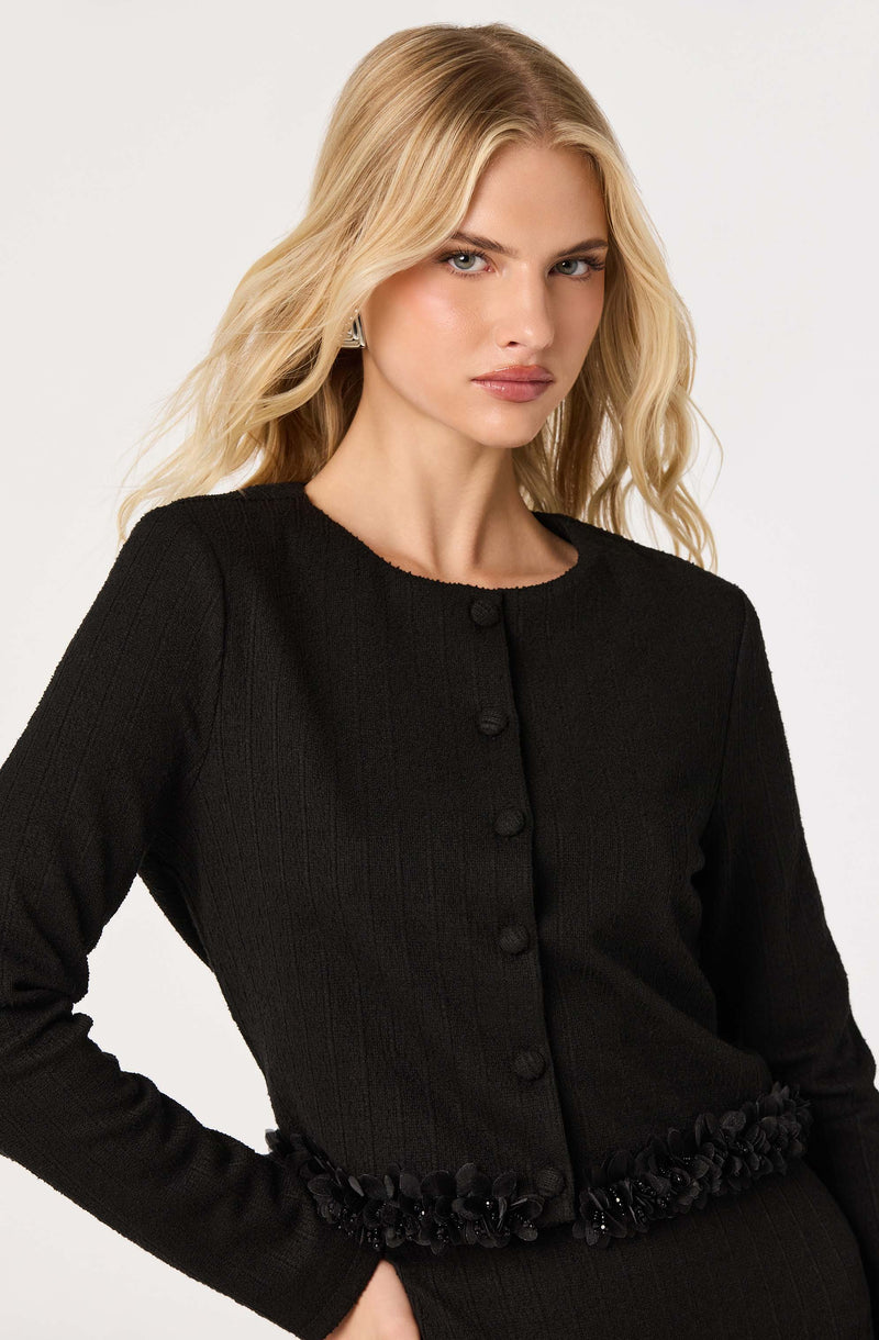 Black long-sleeve cardigan with buttons and floral embellishment at the waist.