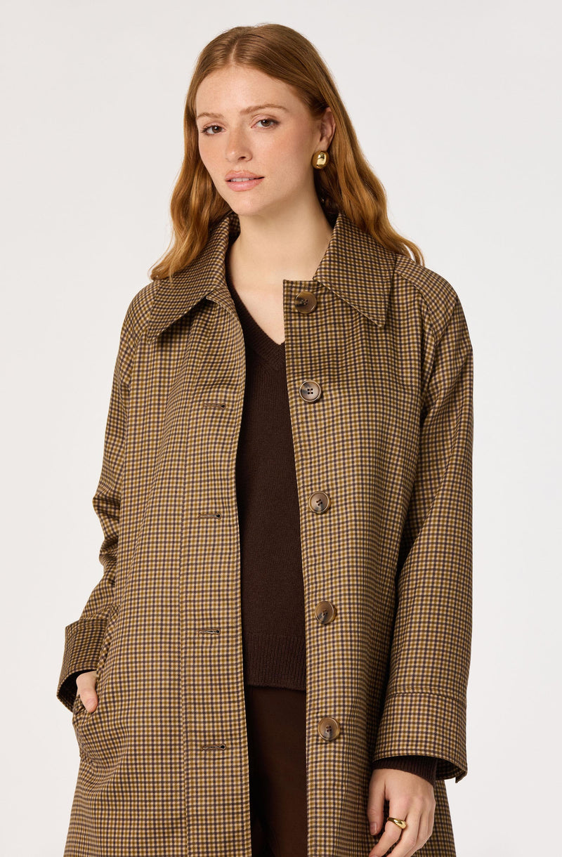 Woman wearing a brown and yellow checkered coat over a dark brown sweater.
