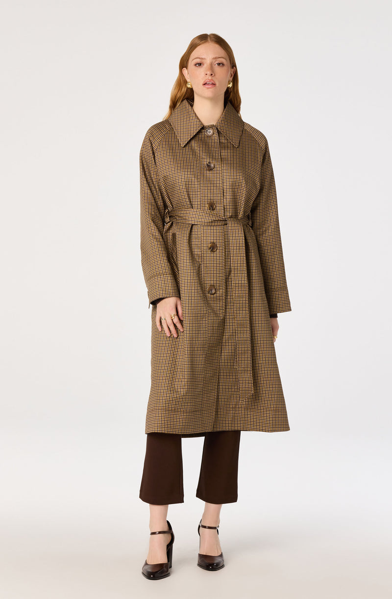 Woman wearing a brown checkered trench coat with large buttons, paired with dark brown pants and black heels.