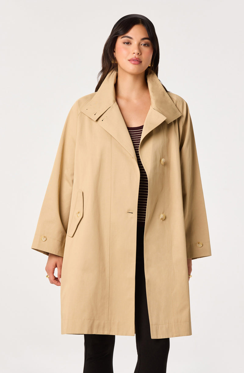 Woman wearing a beige double-breasted trench coat with large collar, long sleeves, and side pockets.