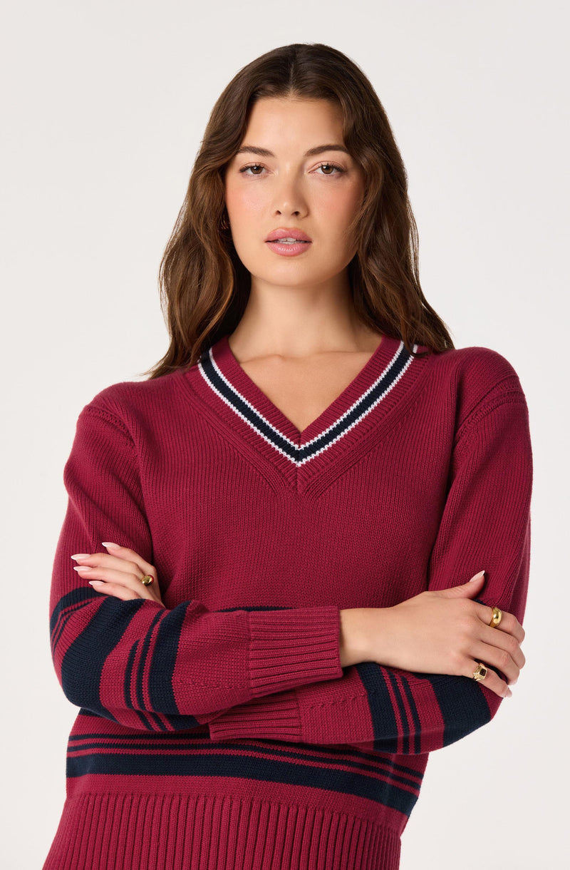 Woman in a red V-neck sweater with black and white stripe details and patterned black and red sleeves.