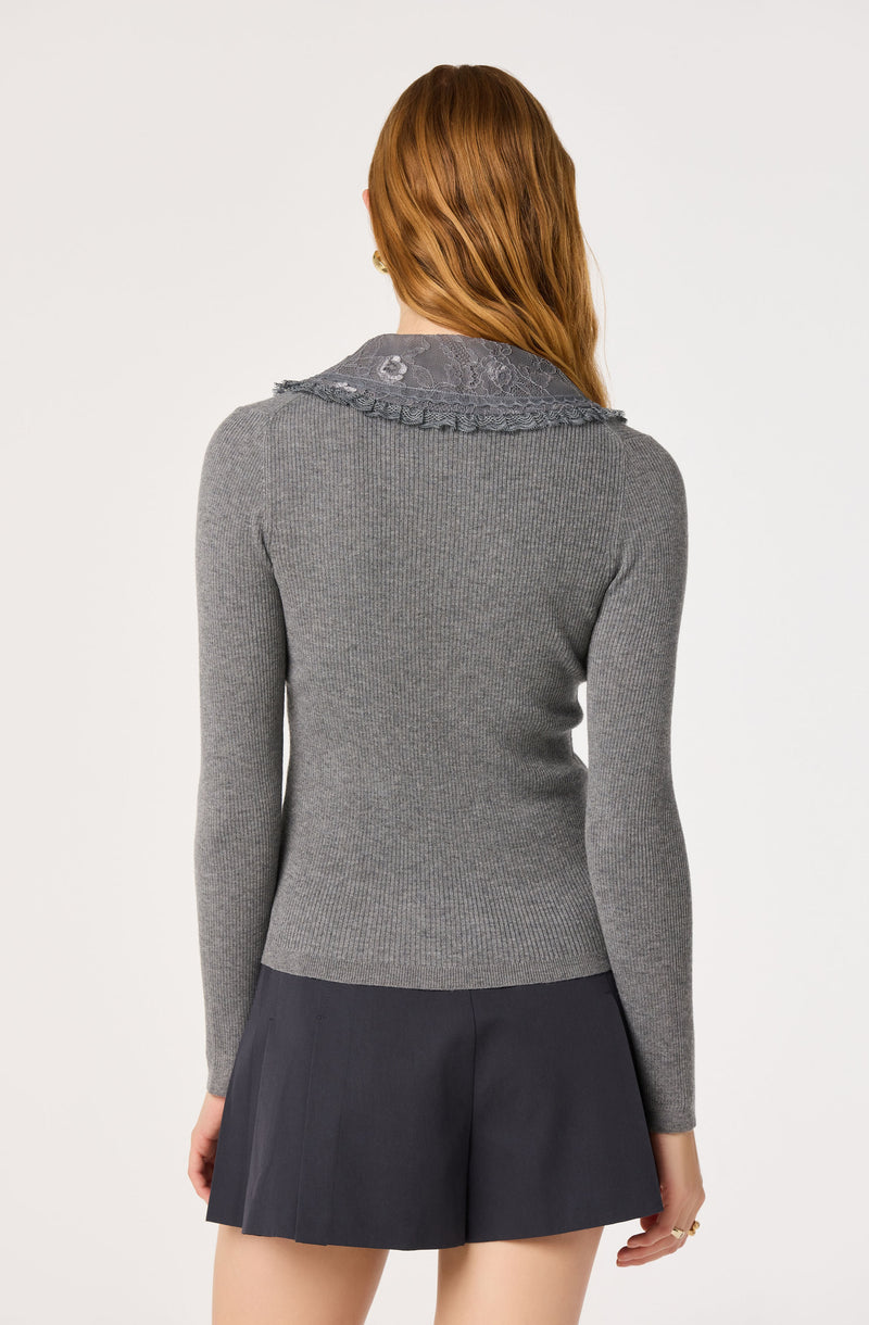 Gray fitted ribbed sweater with a lace collar and ruffle details, paired with a dark pleated skirt.