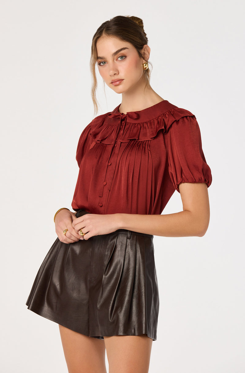 Woman in red ruffled blouse and dark leather skirt.
