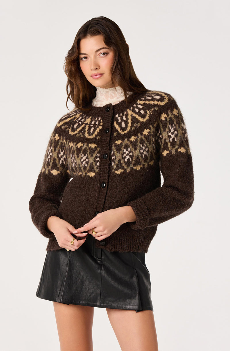 Woman wearing a brown patterned knit cardigan over a white lace turtleneck and a black leather skirt.