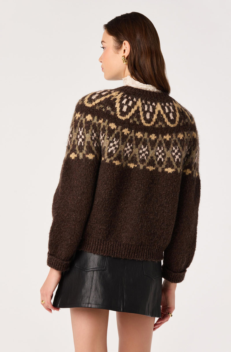 Woman wearing a brown patterned sweater and a black leather skirt, photographed from the back.