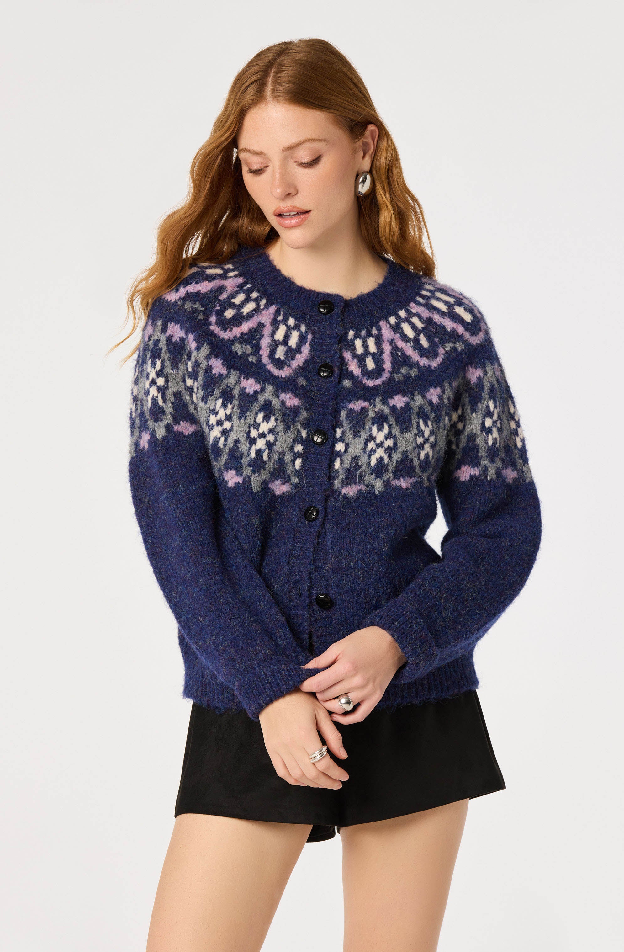 Woman wearing a blue, patterned knit sweater with butterfly design and a black skirt.