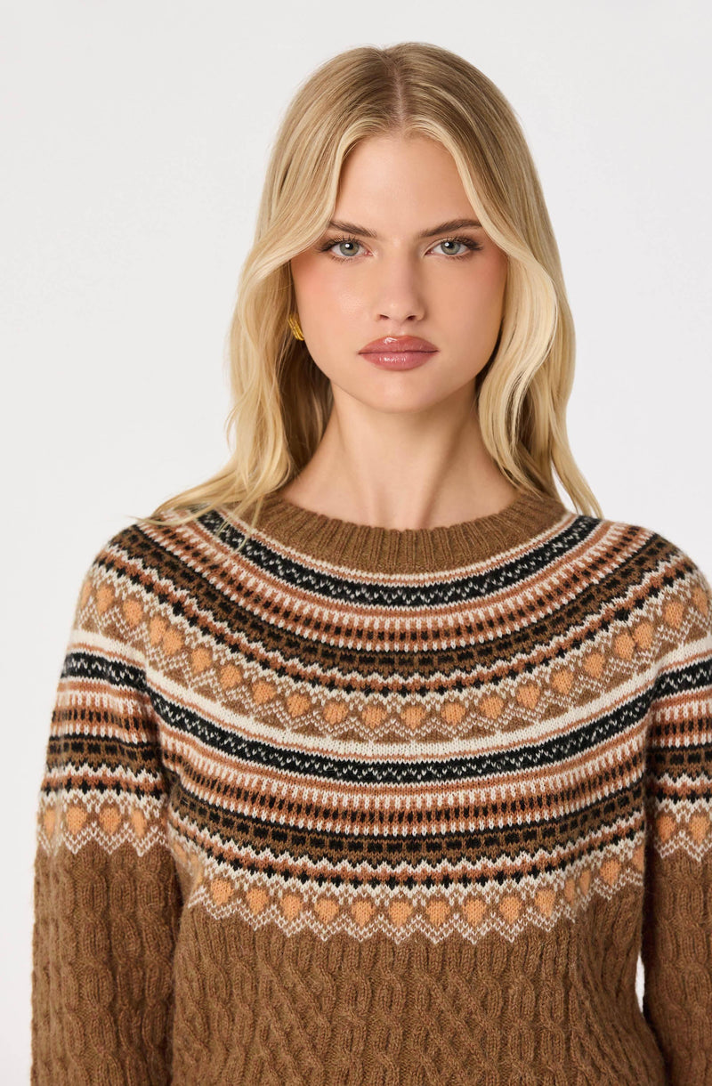 Woman wearing a patterned knit sweater with earthy tones and intricate designs.