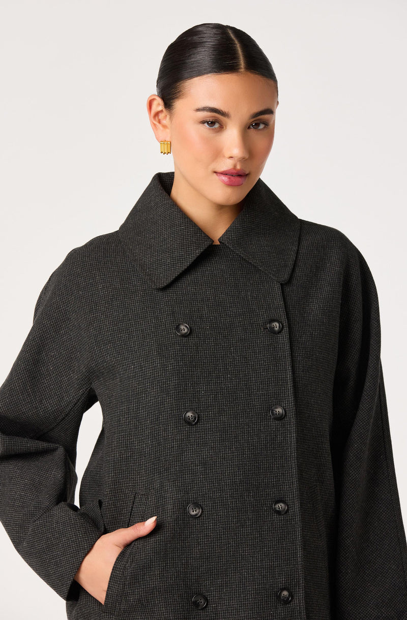 Woman wearing a dark, double-breasted coat with a wide collar.