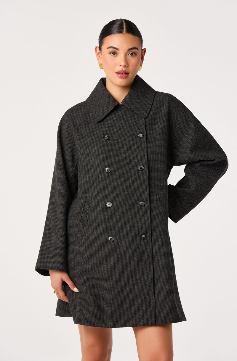 Woman in a dark gray, double-breasted coat with a wide collar and long sleeves.