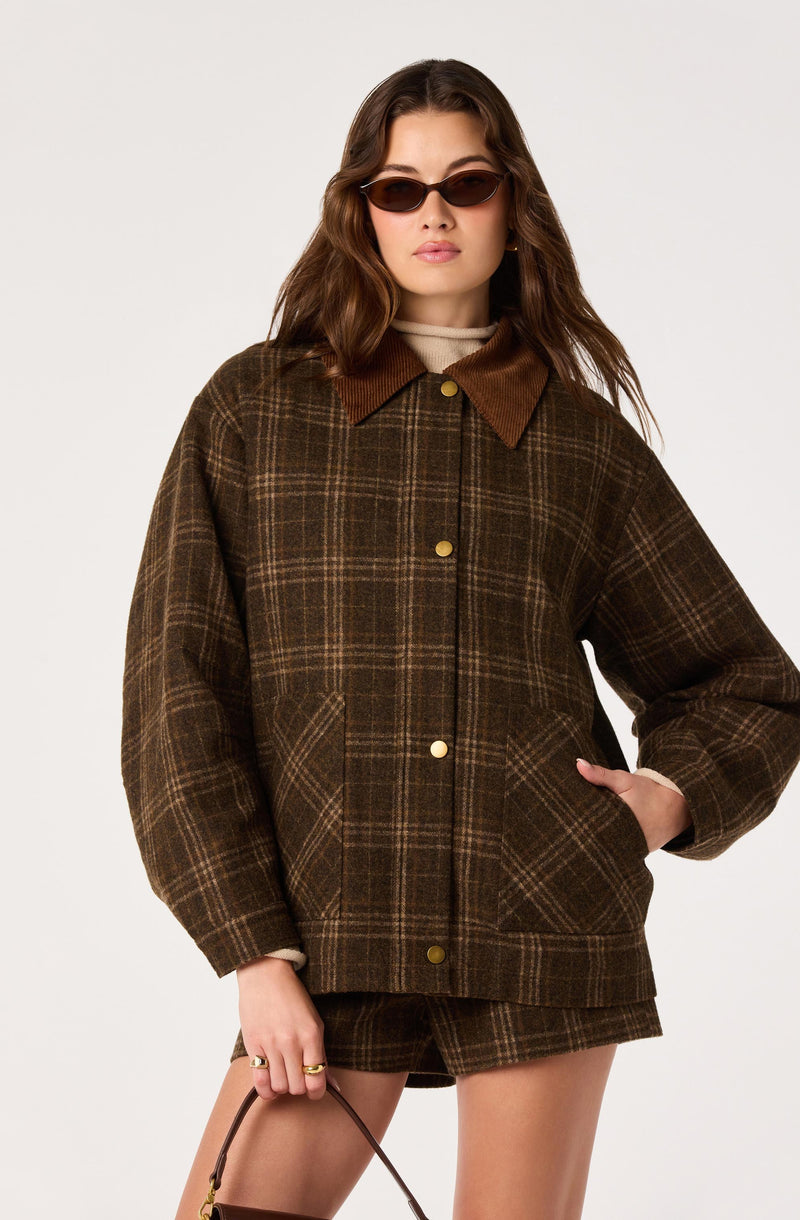 Woman wearing a brown plaid jacket with a collar and gold buttons, paired with matching shorts.