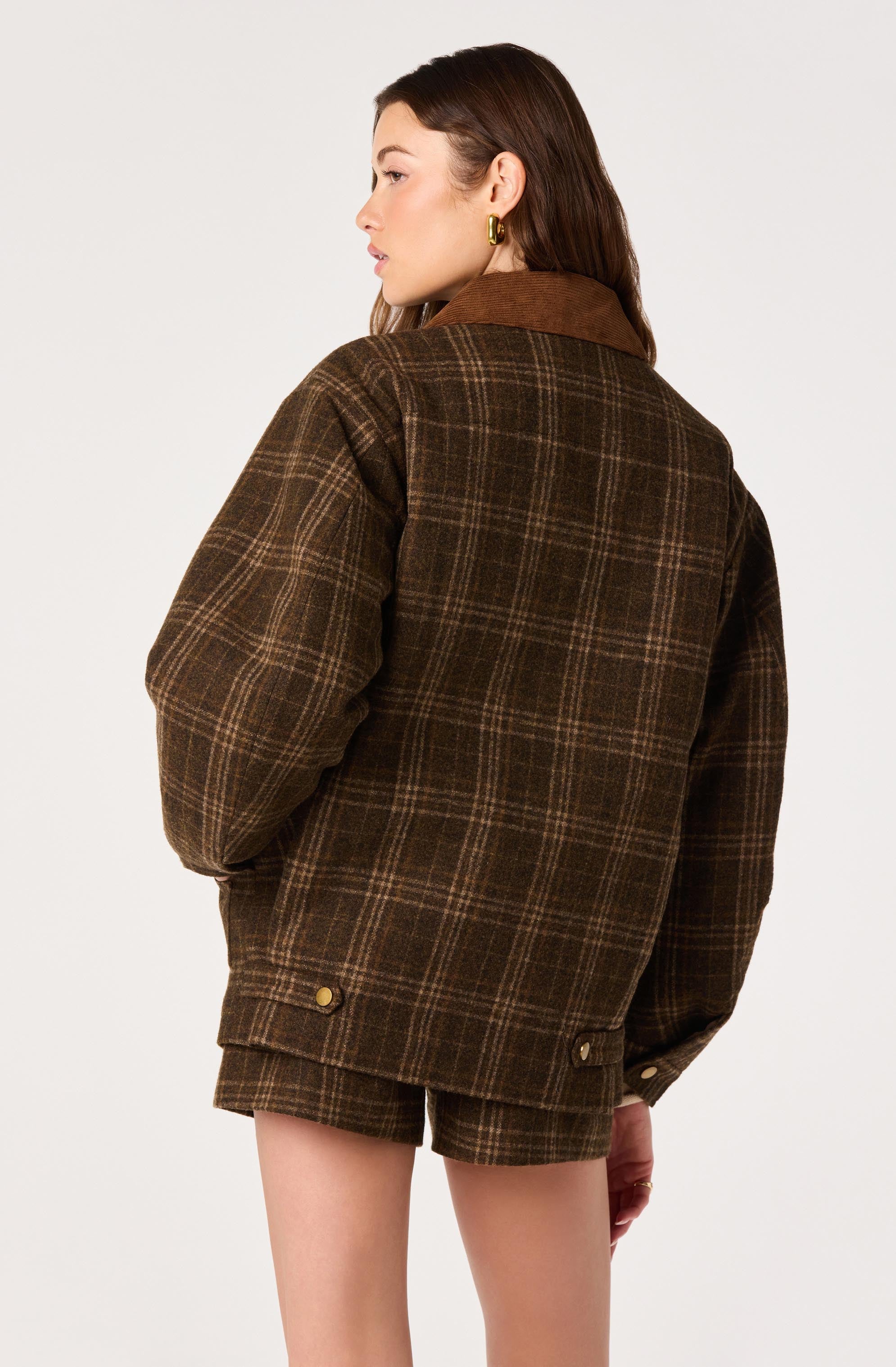 Woman wearing a brown plaid jacket and matching plaid shorts.