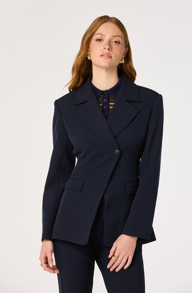 Woman wearing a navy blazer and matching navy blazer, with a plaid shirt underneath.