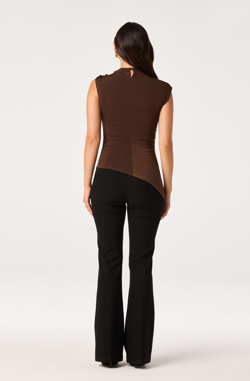 Woman wearing a sleeveless brown top and black pants, facing away.