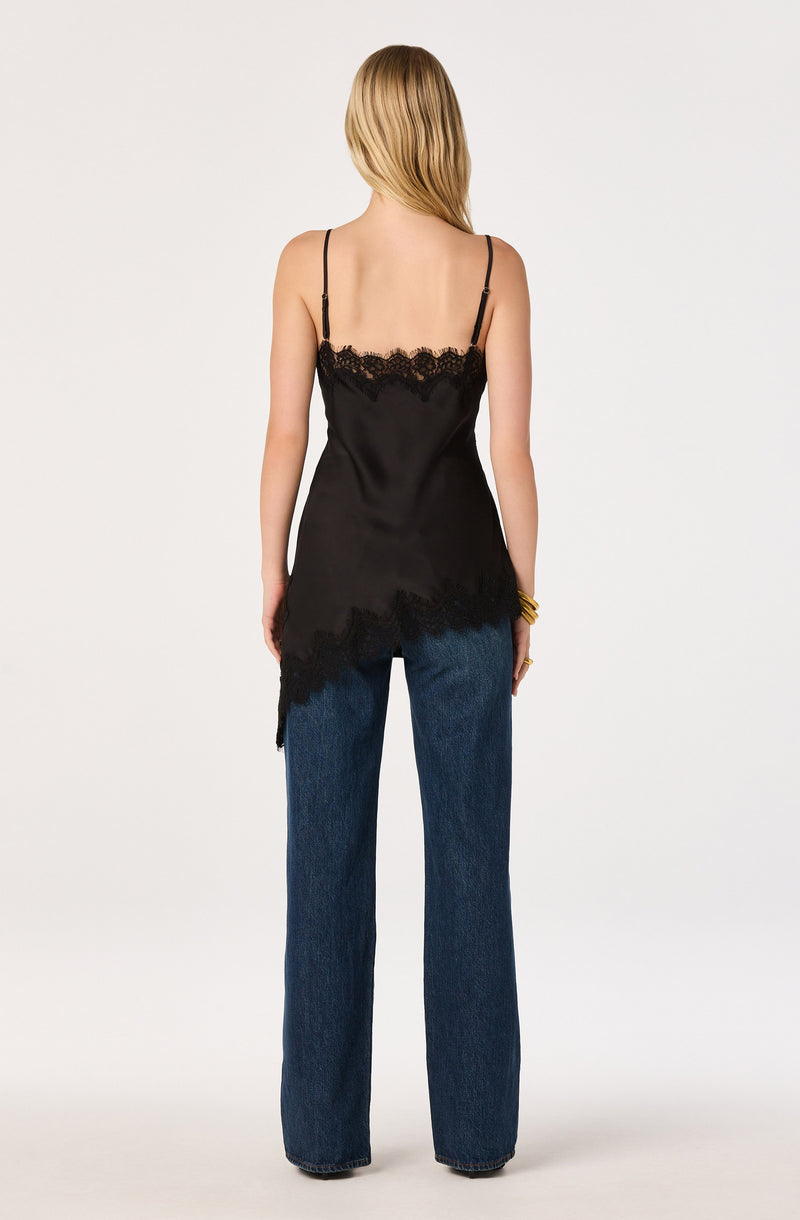 Woman wearing a black slip top with lace trim and wide-leg blue jeans.