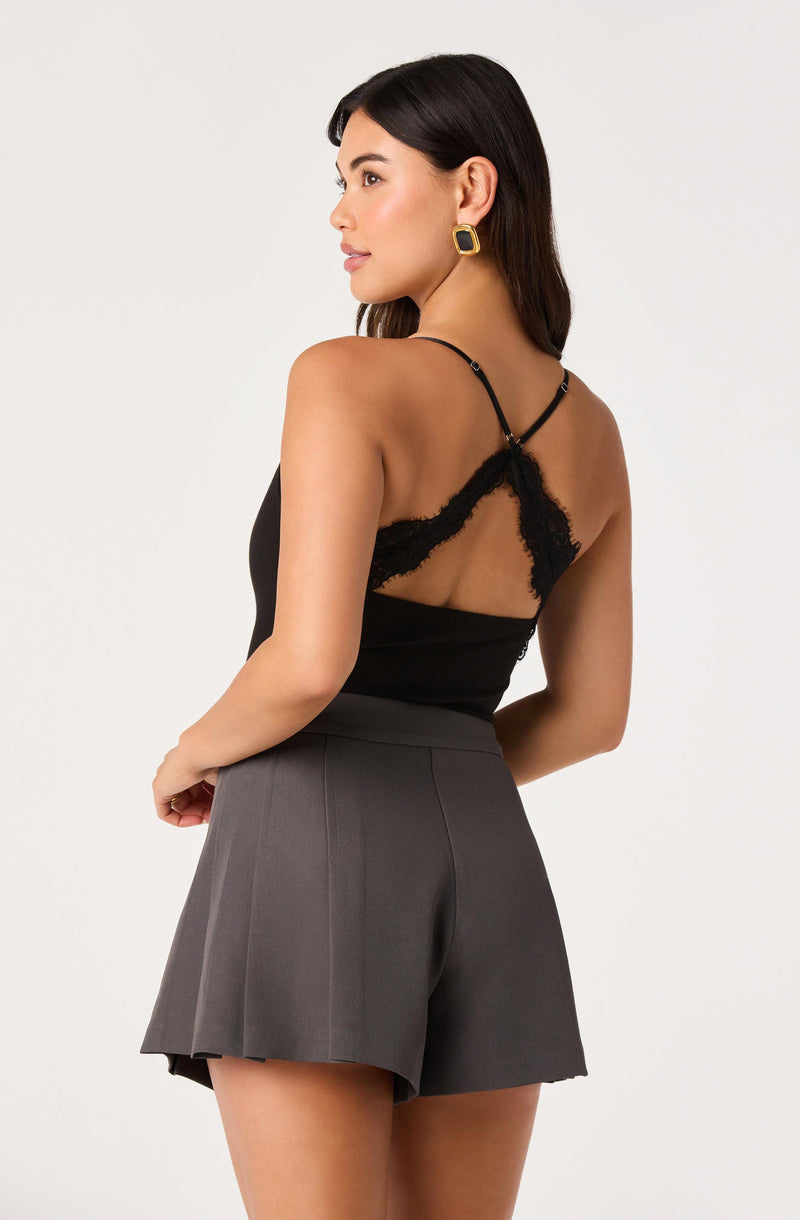 Woman wearing a black lace-back camisole top and high-waisted gray shorts.