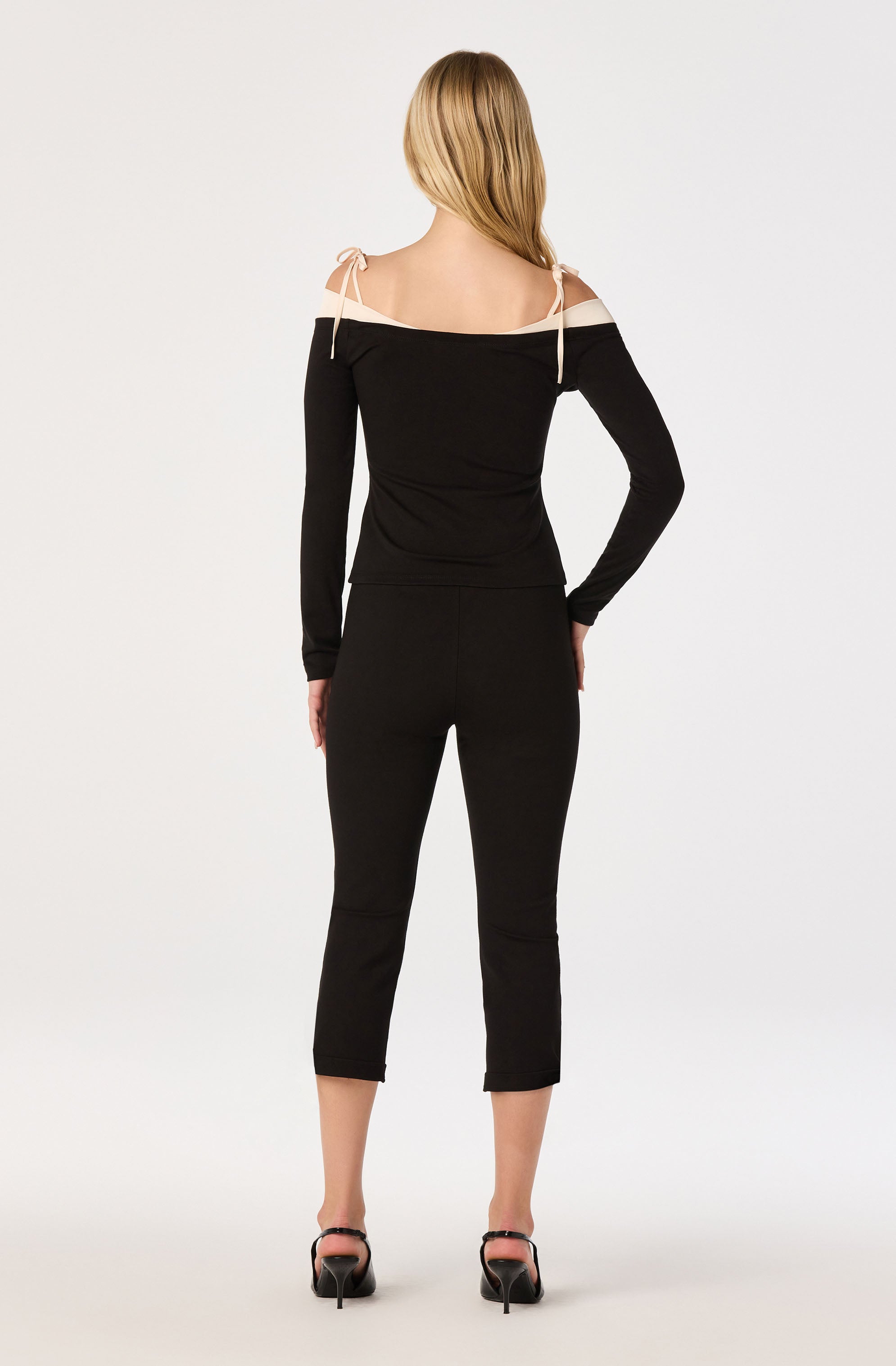 Black off-shoulder top with beige shoulder accents and matching black pants, high heels.