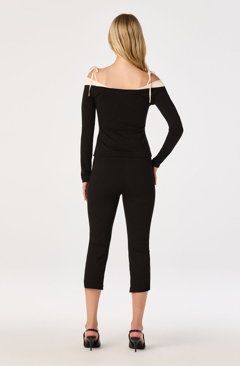 Black off-shoulder top with beige shoulder accents and matching black pants, high heels.