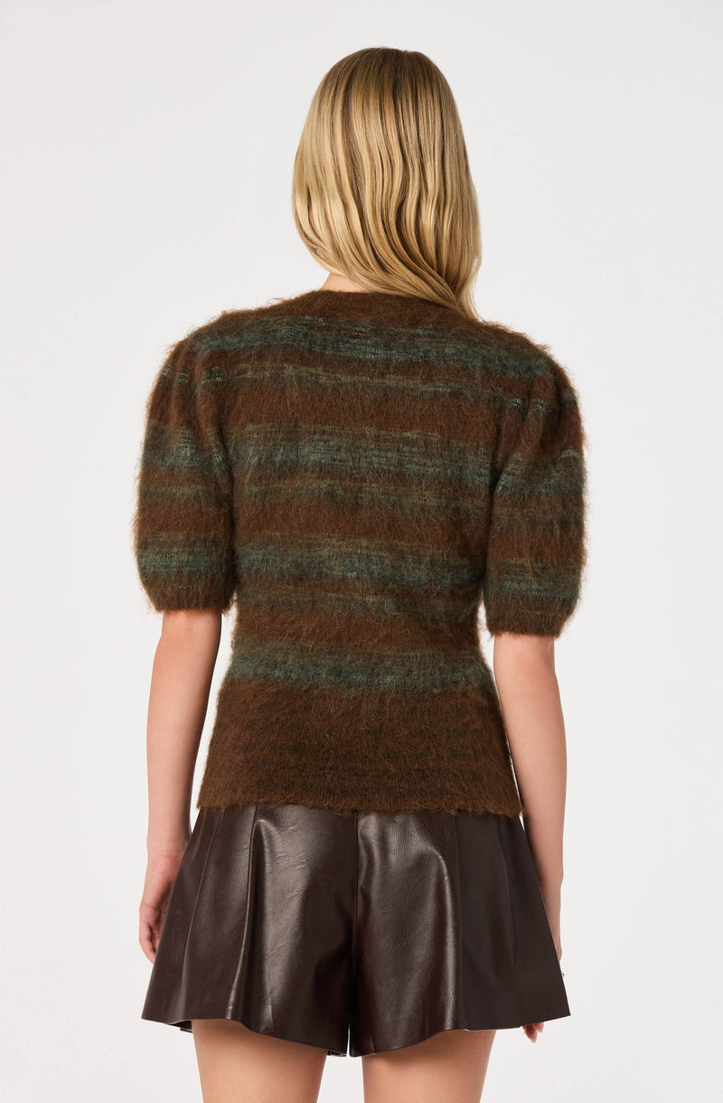 Woman wearing a multicolored striped fuzzy sweater with puffed short sleeves and dark leather shorts.