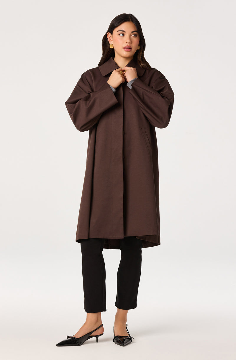 Woman in a long brown coat, black pants, and black heels.