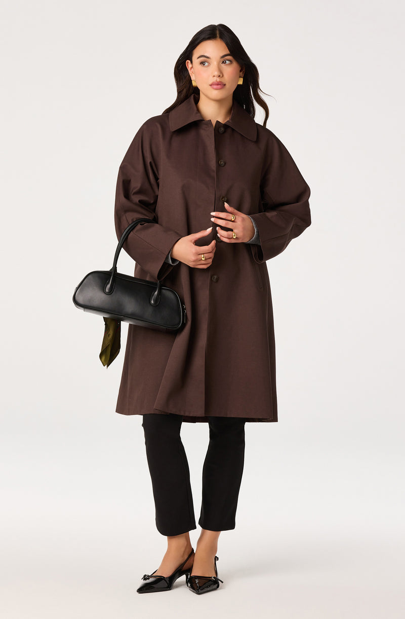 Woman wearing a brown oversized coat, black pants, black heels, and carrying a black handbag.