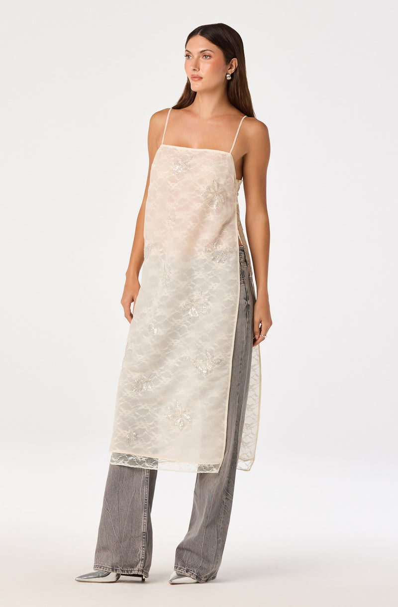 Cream-colored slip dress with spaghetti straps over gray wide-leg jeans.