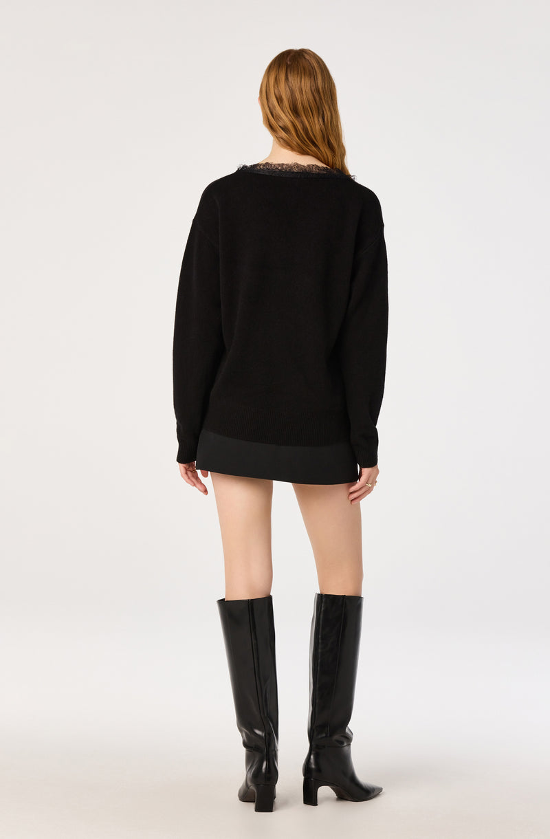 Woman in black sweater, short skirt, and tall black boots, facing away.