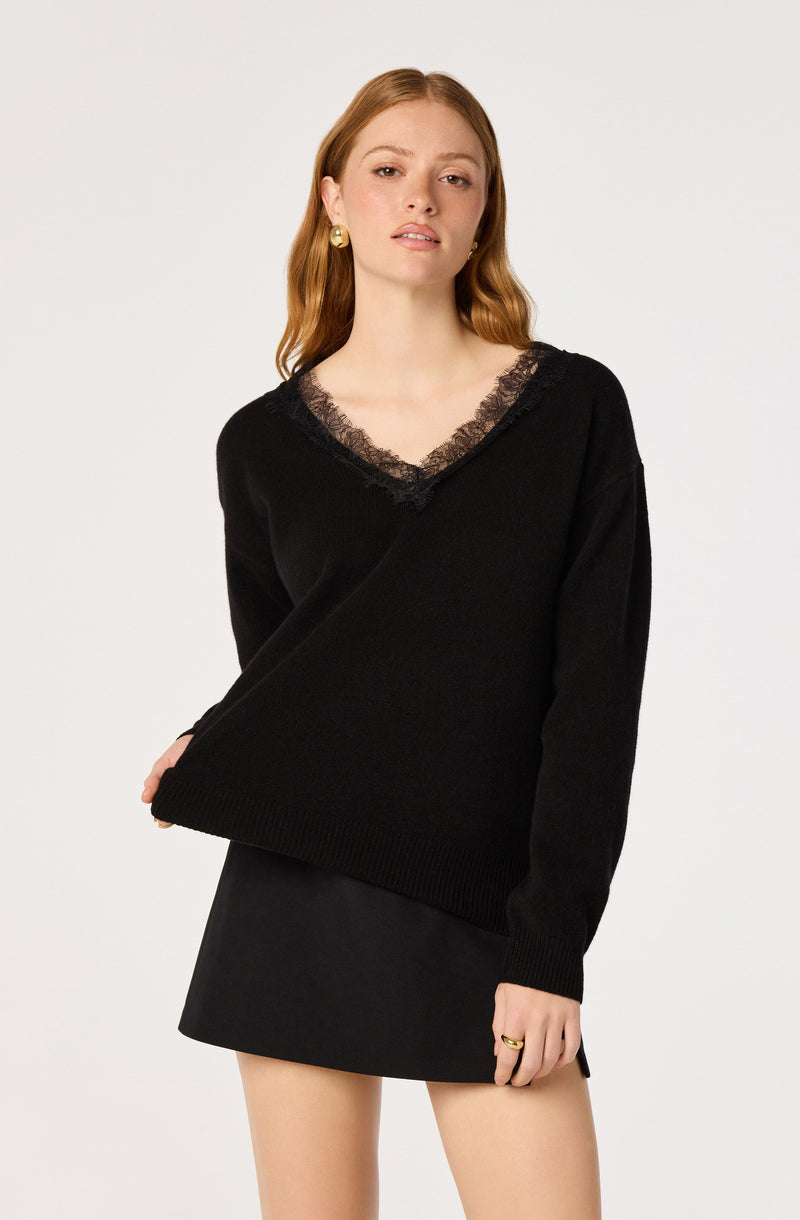 Woman wearing a black sweater with lace trim at the neckline, paired with a black skirt.