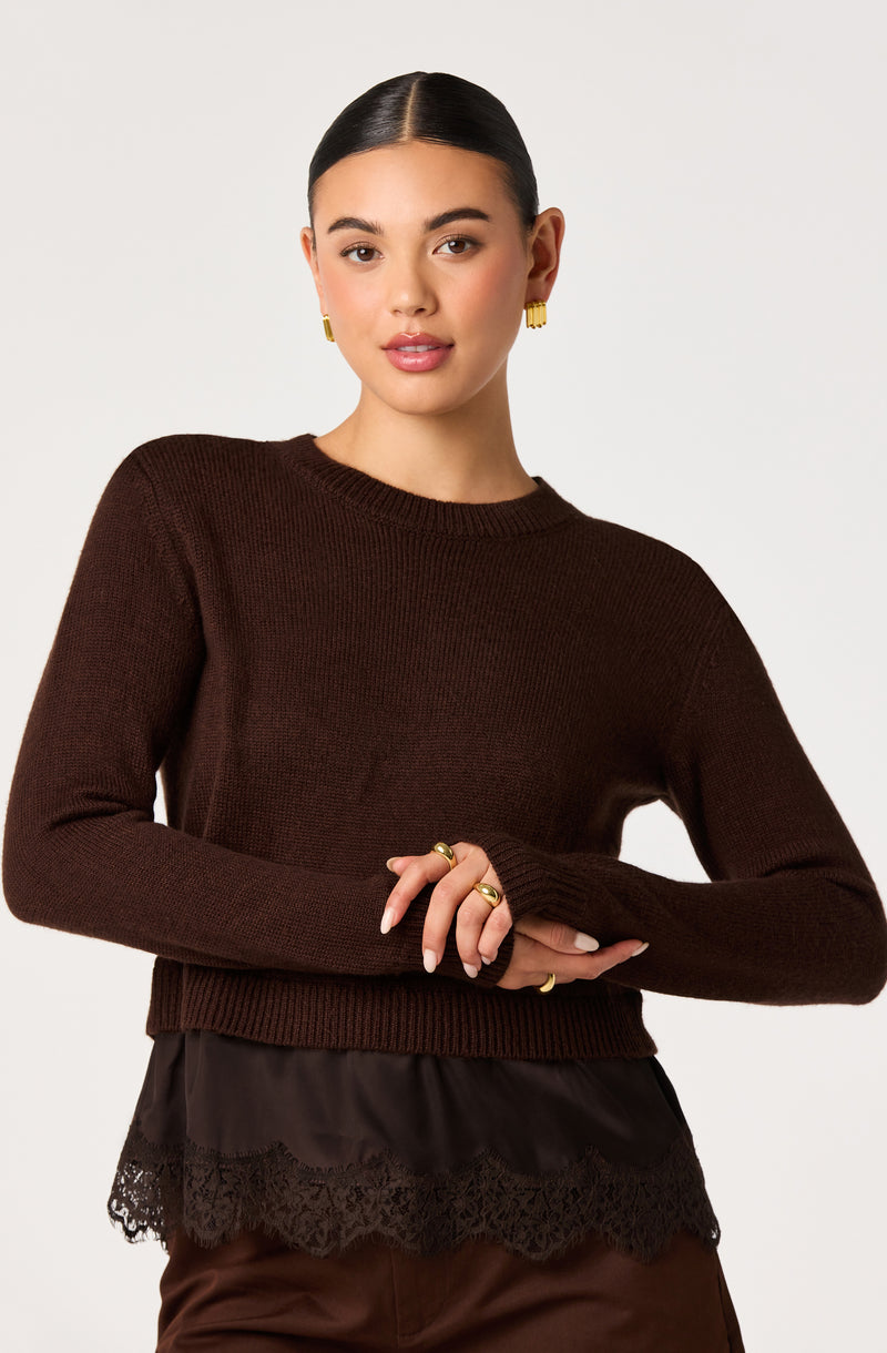 Woman wearing a dark brown knit sweater with layered lace trim at the bottom.