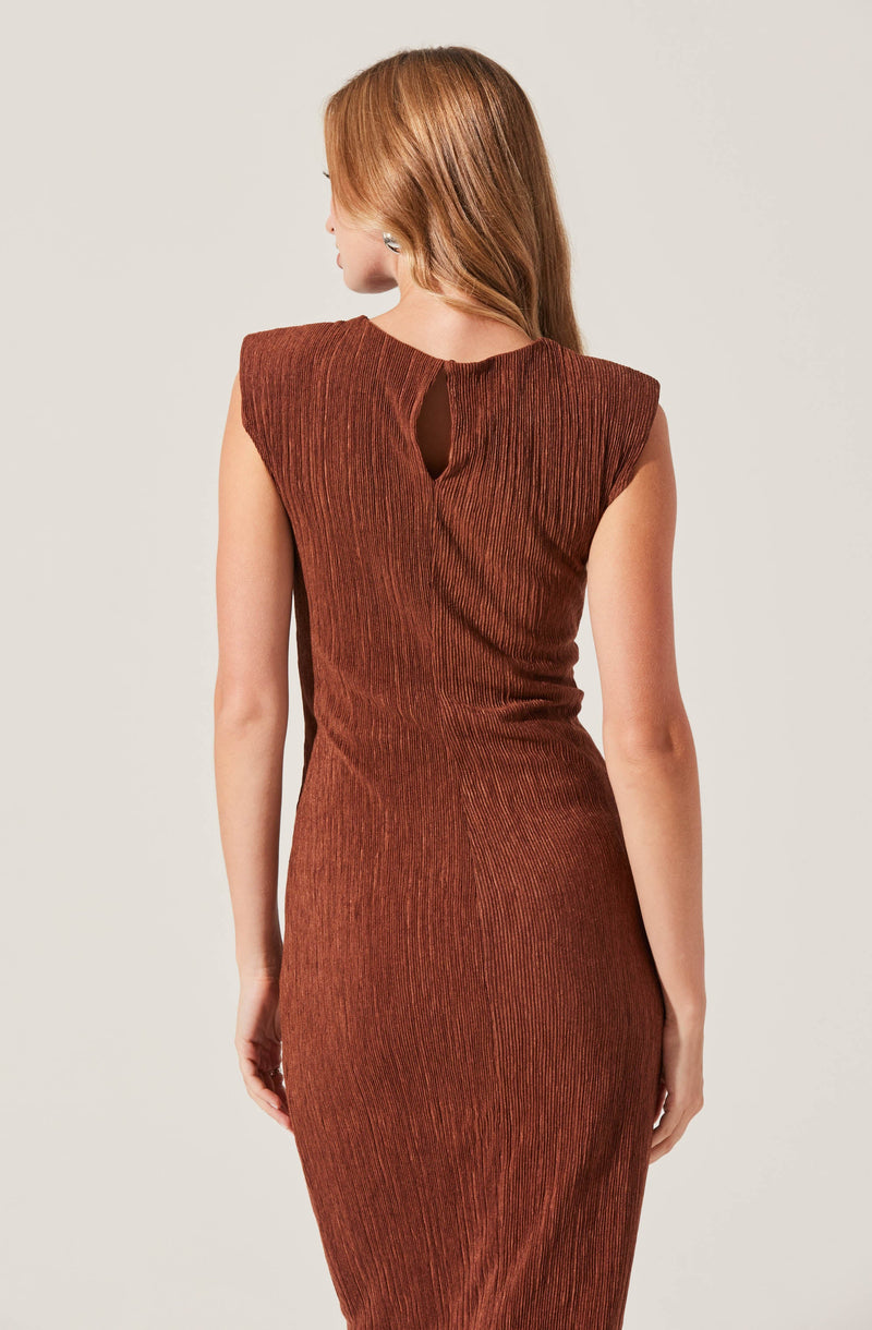 A woman wearing a sleeveless, fitted dress in a textured, metallic rust color with a slight sheen. The dress features a small keyhole opening at the back neckline.