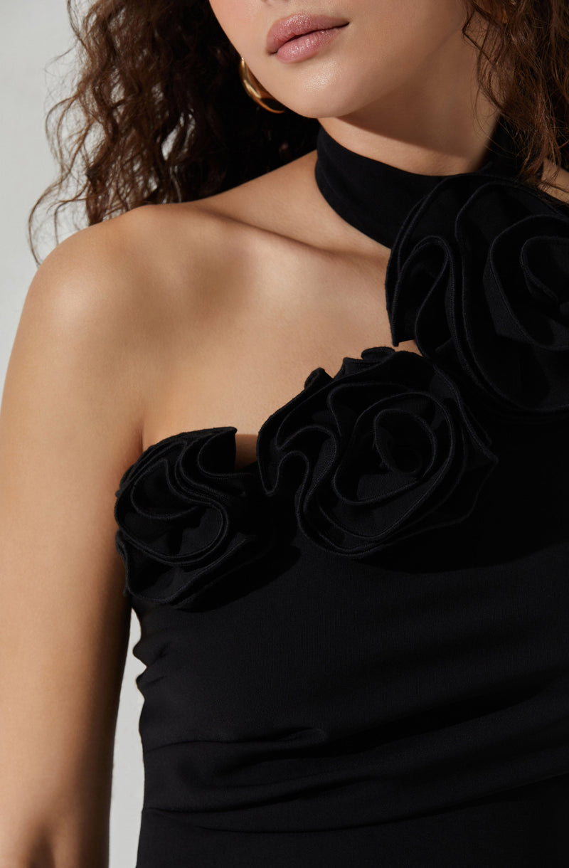 A woman is wearing a black strapless dress with decorative fabric flowers on the bodice and a matching black choker with large fabric flowers.