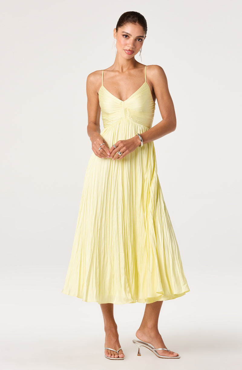 Woman in a light yellow pleated dress with spaghetti straps.