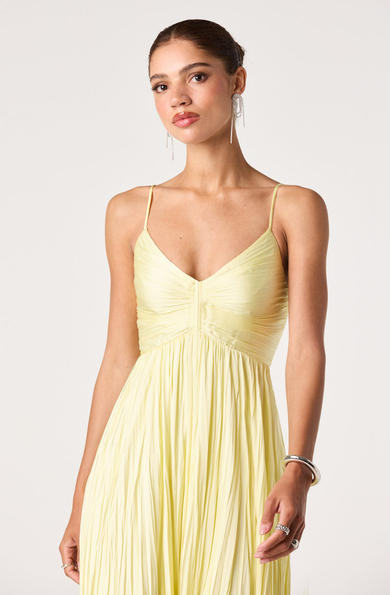 Light yellow pleated dress with a fitted bodice and thin spaghetti straps.