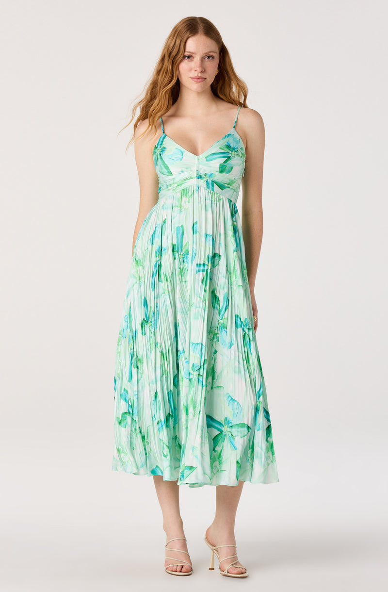 Woman in a sleeveless, floral-print sundress with spaghetti straps and a pleated skirt.