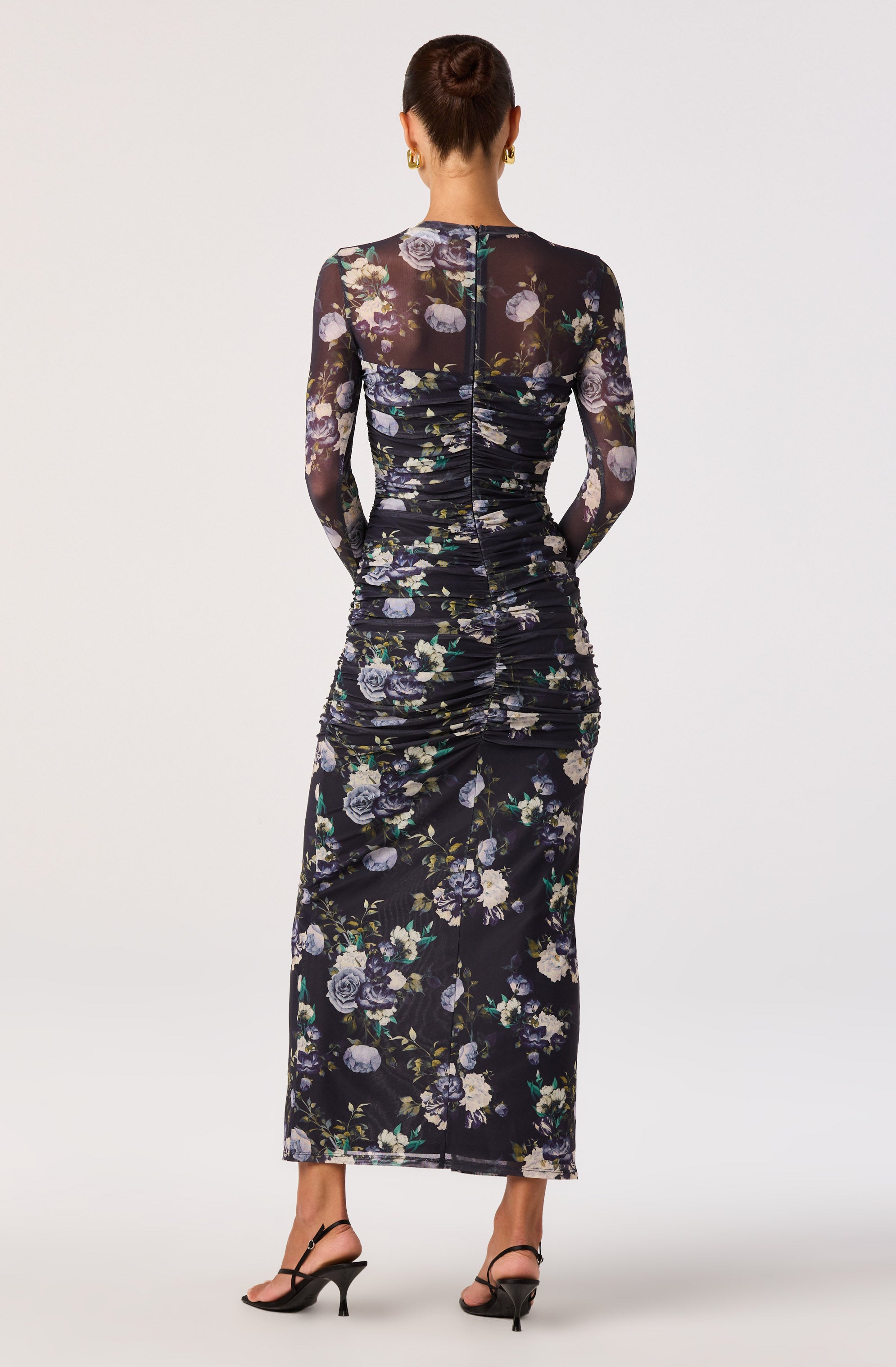Black floral dress with long sheer sleeves and a ruched design, paired with black high-heeled sandals.