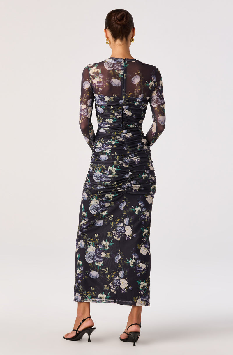 Black floral dress with long sheer sleeves and a ruched design, paired with black high-heeled sandals.