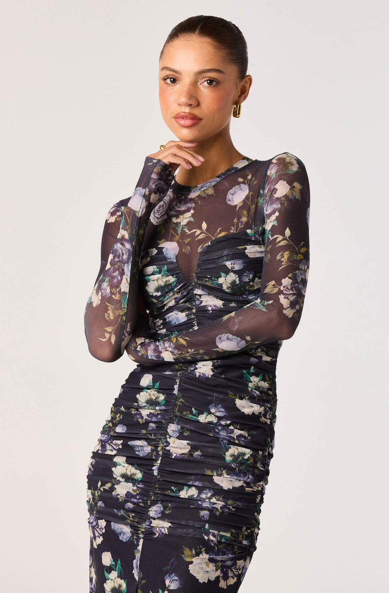 Woman wearing a long-sleeve, floral-patterned, ruched dress with sheer fabric.
