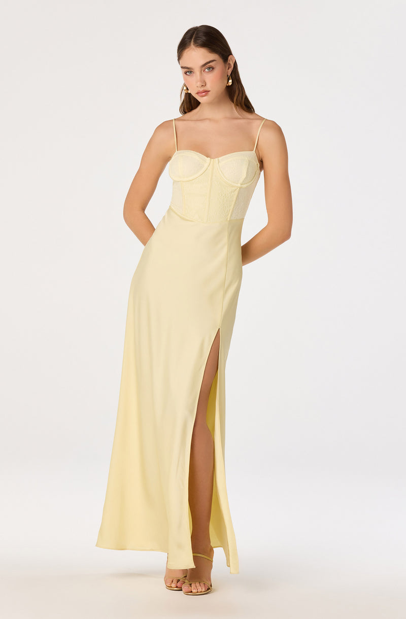 Woman in a light yellow, floor-length dress with spaghetti straps and a high slit.