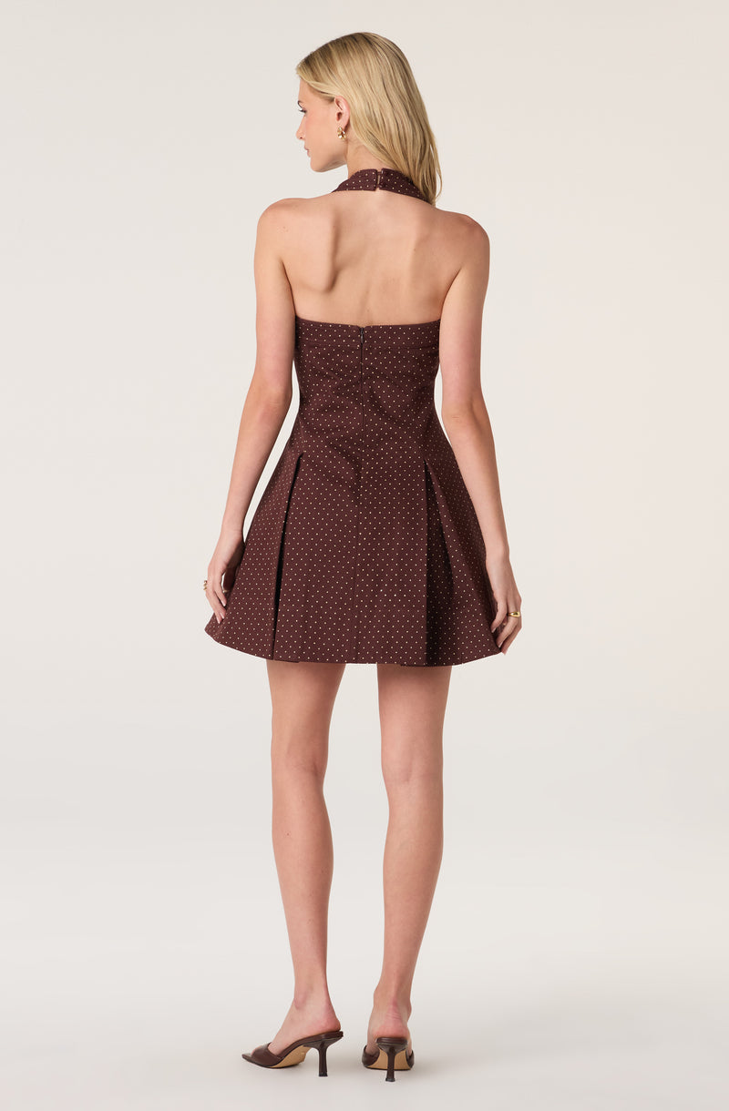 Back view of a woman wearing a strapless, dark brown dress with small white polka dots and a matching halter neck.