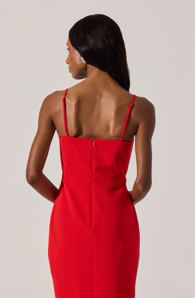 A woman is wearing a form-fitting, sleeveless red dress with thin spaghetti straps. The dress has a zipper at the back and a smooth, elegant fabric.