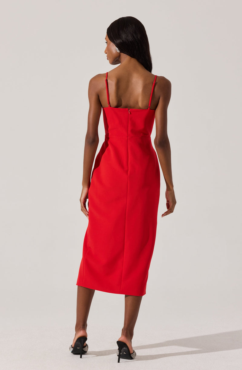 A woman is wearing a sleeveless, ankle-length red dress with thin shoulder straps. The dress has a fitted bodice and a straight silhouette that reaches mid-calf. She is also wearing black high-heeled shoes.