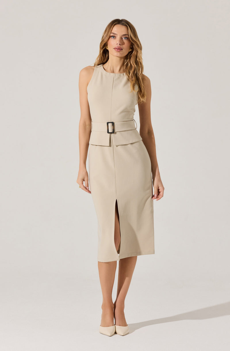 A woman is wearing a sleeveless, beige midi dress with a fitted waist accented by a wide belt with a large rectangular buckle. The dress features a front slit at the hem, adding a stylish detail. She is also wearing high-heeled shoes that match the color of the dress.