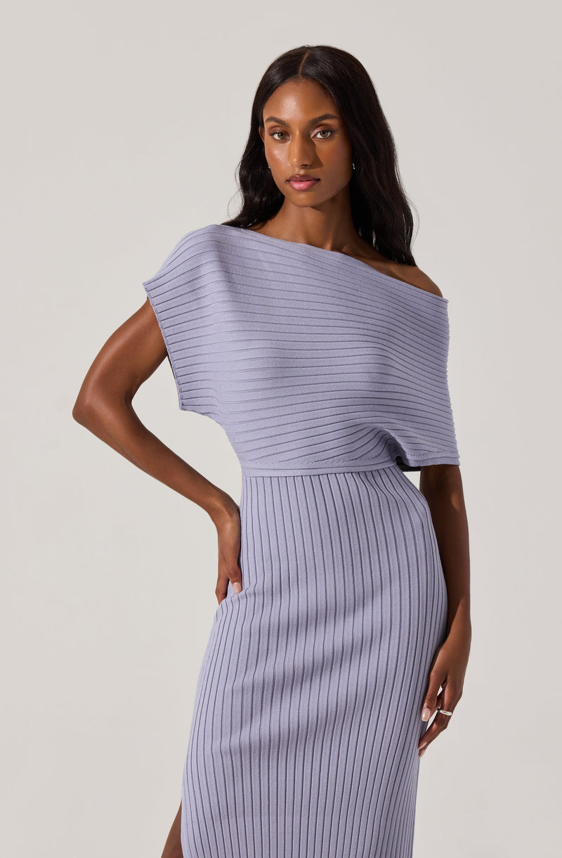 A woman is wearing a light purple, ribbed knit dress with a wide, off-the-shoulder neckline and a fitted skirt that extends to the ankles. The top part of the dress has horizontal ribbing, while the skirt features vertical ribbing.