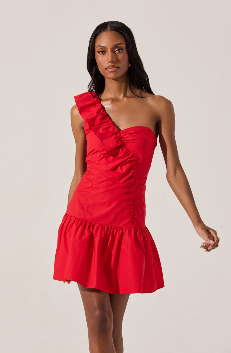 A woman is wearing a bright red, one-shoulder dress featuring a large ruffle detail along the shoulder strap, a fitted bodice with ruching, and a flounced hemline.