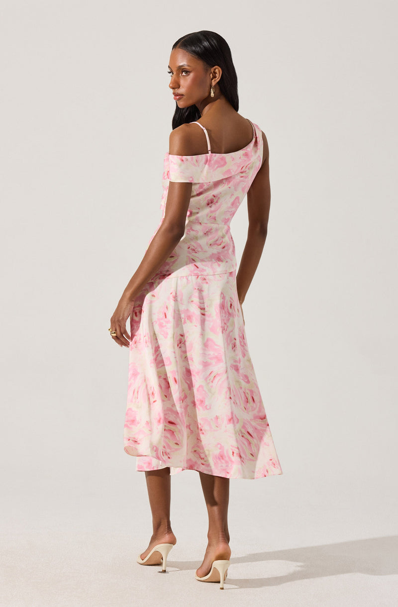 A woman is wearing an off-the-shoulder dress with spaghetti straps. The dress has a pink and white marbled pattern, fitting snugly at the top and flowing into a midi-length skirt. She is also wearing nude high-heeled shoes.