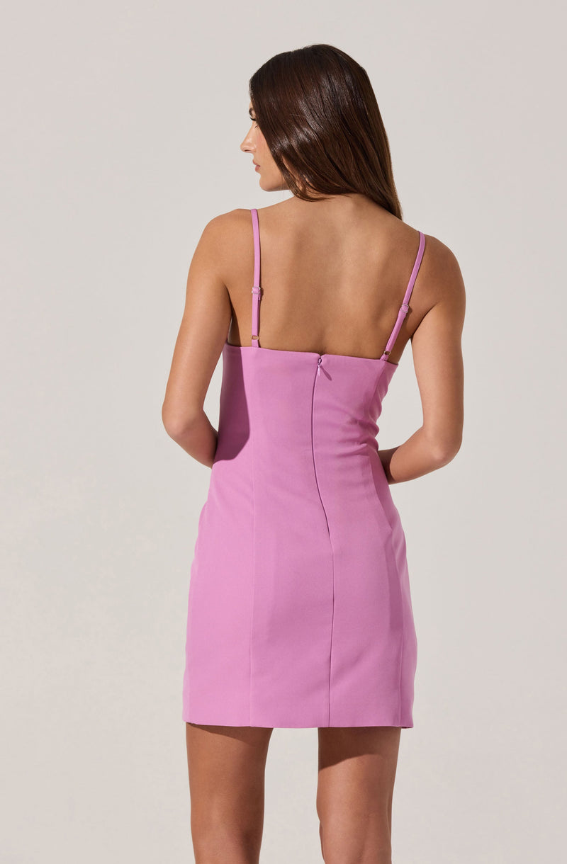 A woman is wearing a fitted, sleeveless, pink dress with spaghetti straps. The dress is made of a smooth fabric and has a back zipper closure.