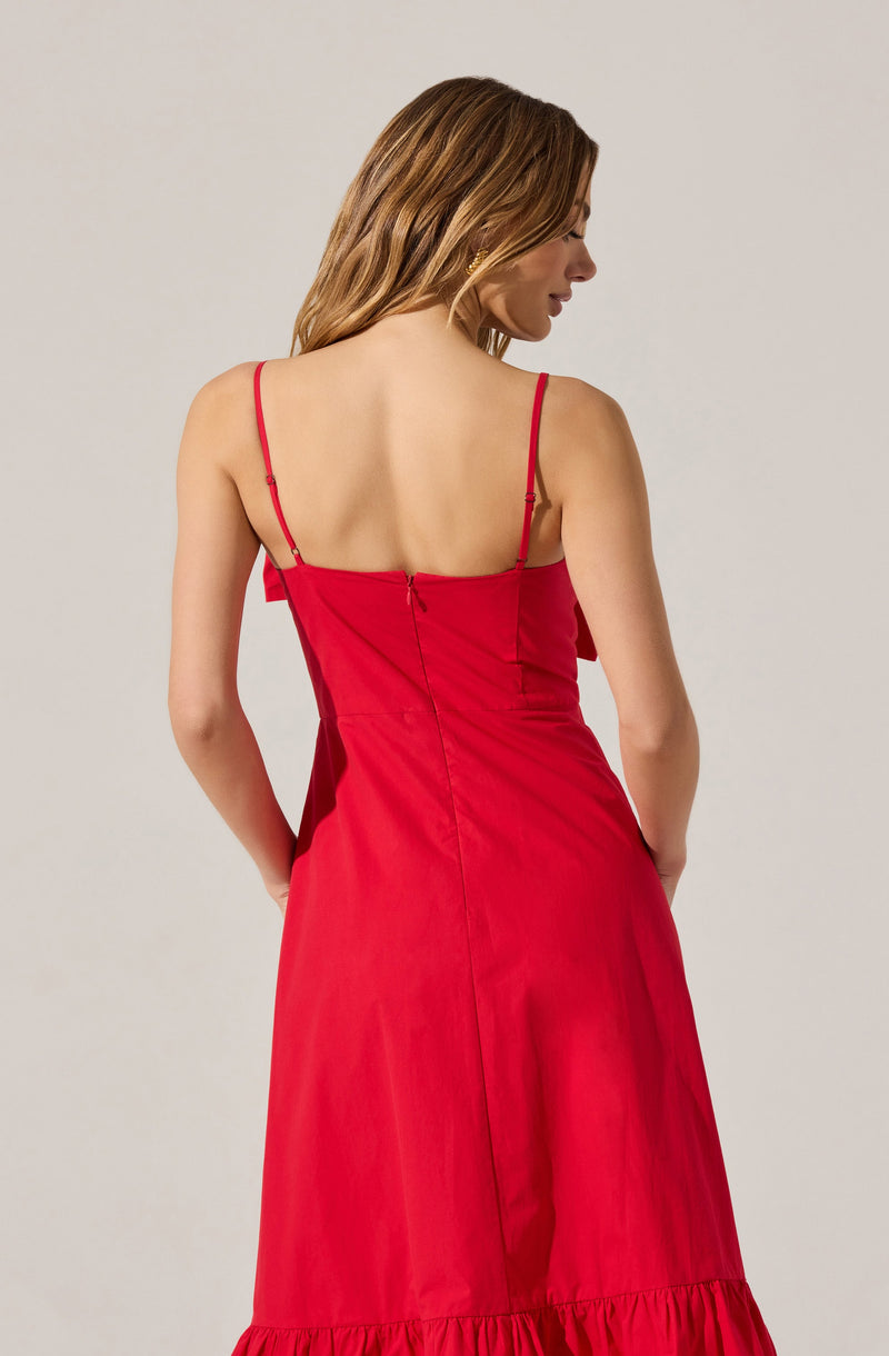The dress is a bright red, sleeveless with thin spaghetti straps. It has a fitted bodice and a slightly flared skirt with a ruffle hem at the bottom. The fabric appears smooth and lightweight.