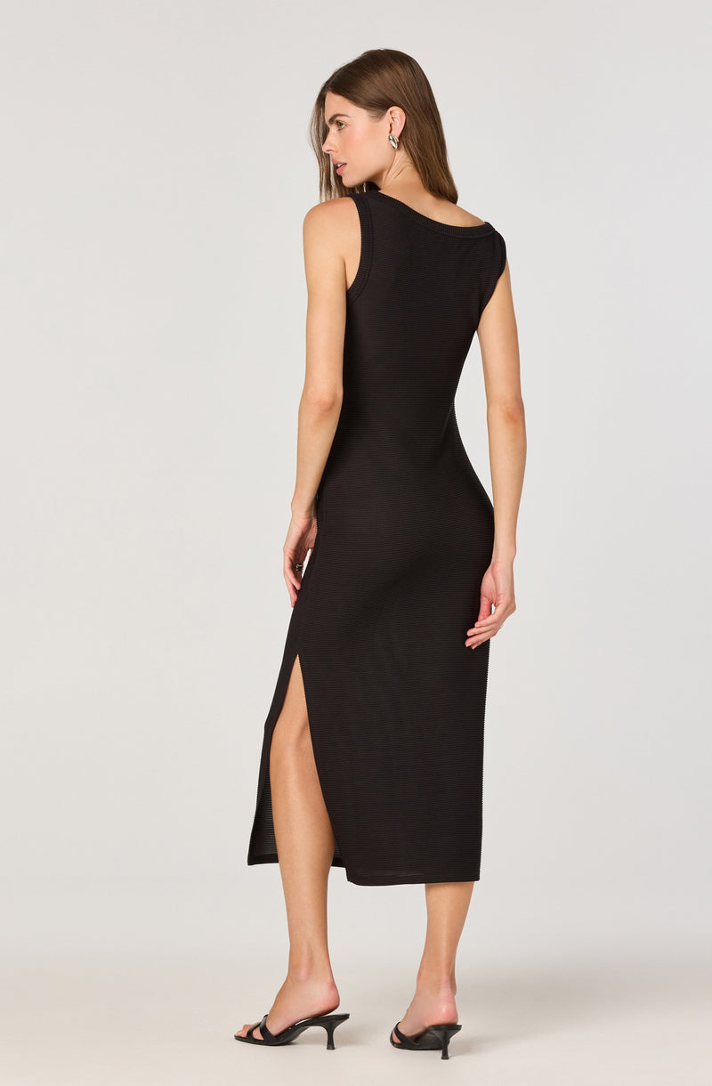 A woman is wearing a sleeveless, black, knit midi dress with a round neckline and side slit up to the knee. She has on black open-toe high heels with thin straps.