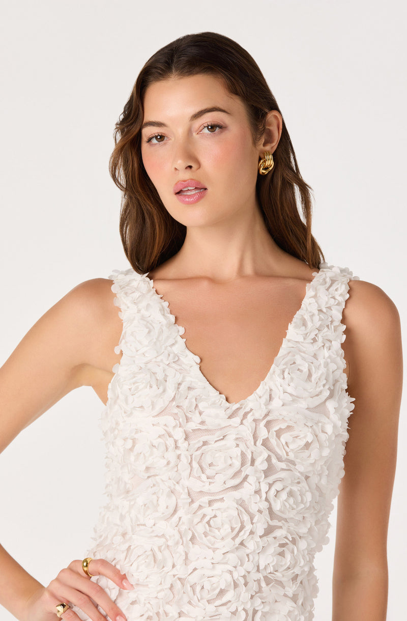 Woman wearing a sleeveless white top with textured floral details.