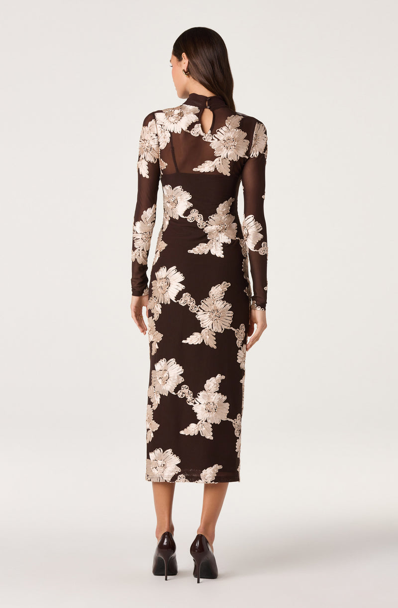 Long black dress with beige floral embroidery, sheer long sleeves, and a high neckline.